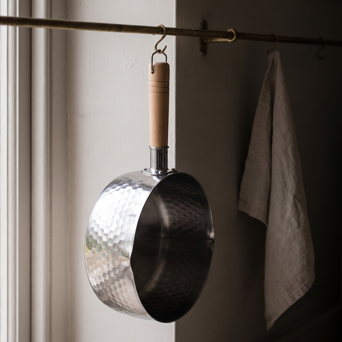 The saucepan hanging from a brass rail by the wire loop on its handle