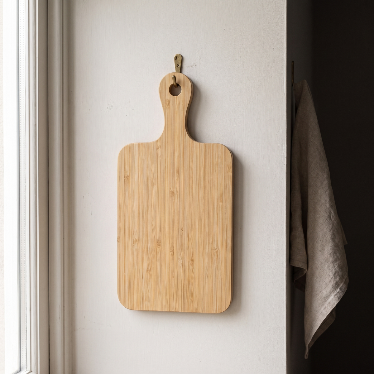 The board hanging from a brass hook by the hole in its handle