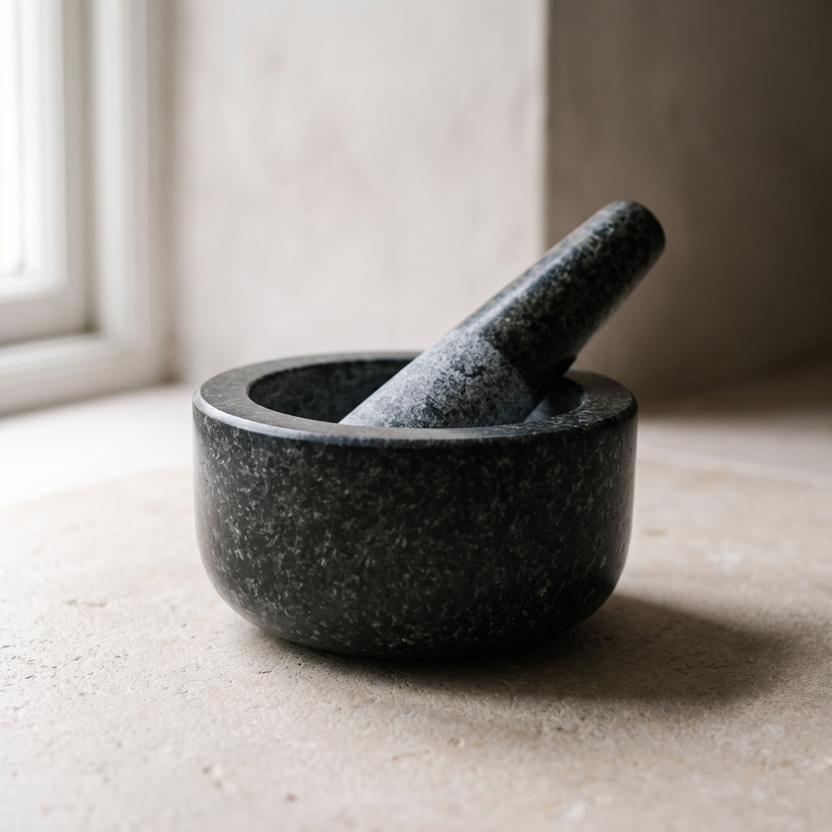 Granite mortar and pestle on a limestone worktop in soft daylight