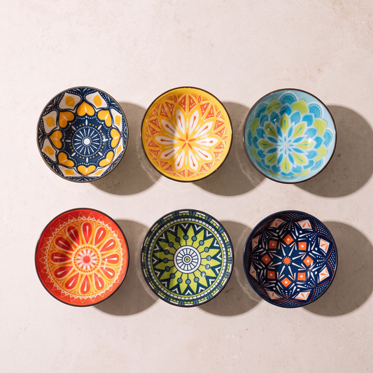 Six hand painted bohemian bowls laid out in two rows on a limestone worktop