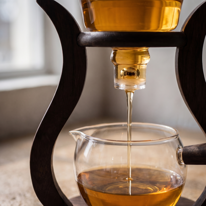 Close view of the glass spout with brewed tea running down into the carafe