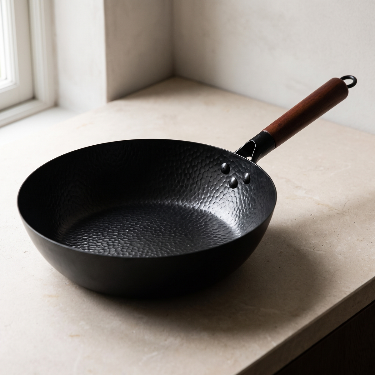 The iron wok and its wooden handle seen from a three quarter angle
