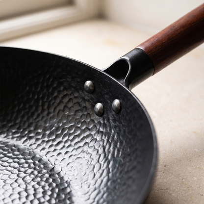 Close view of the hammered iron surface and the riveted wooden handle join
