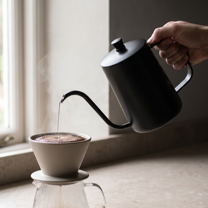 Pouring a thin steady stream into a ceramic dripper over a glass carafe