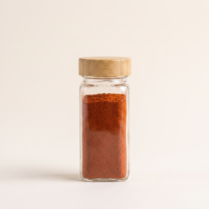 A single jar filled with paprika, showing its round profile and bamboo lid