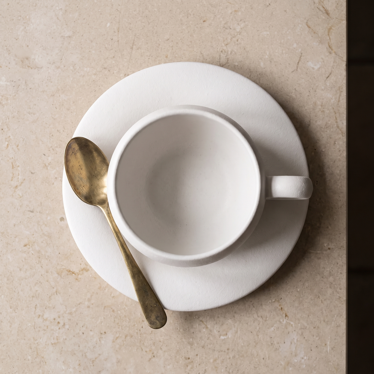 Seen from above, the saucer holding the cup and a brass teaspoon